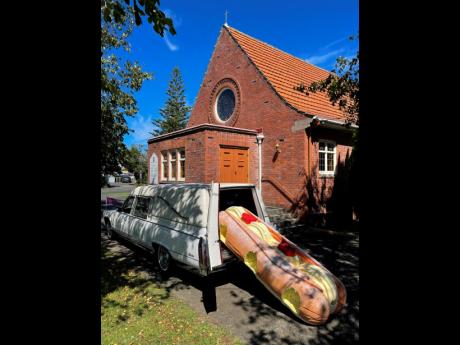 This photo provided by Ross Hall shows a cream doughnut-shaped coffin for the funeral of Phil McLean outside a church in Tauranga, New Zealand, on Feb 17. Auckland company Dying Art makes unique custom caskets which reflect the people who will eventually l