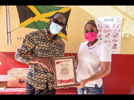 Vice-principal of the Seaview Gardens Primary School in St Andrew, Keisha Heslop-Pessoa, presents dancehall artiste Bounty Killer (birth name Rodney Price) with a token of gratitude after he handed over 40 tablets to the school yesterday.