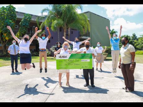 Students jump for joy as the cheque is handed over by Susan Canobie, head of school, American International School of Kingston to Monsignor Gregory Ramkisson. Darcy Tulloch-Williams, executive director, Mustard Seed Communities, looks on. Back, from left: 