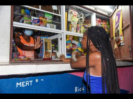 A shopkeeper rejects the cash from a customer at a corner shop on Olympic Way, in Andrew Holness’ St Andrew West Central constituency, on Thursday evening. Corner shop operators are divided on the prime minister’s criticism of COVID-19 breaches.