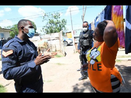 Policemen speak with Annmarie Lawman on Friday about the shooting death of her 16-year-old stepson Joel Lawman two days earlier in Old Harbour, St Catherine. 