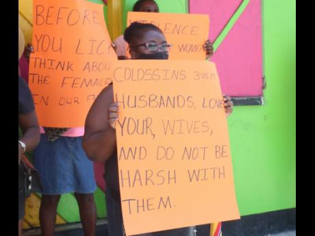 Protesters gather at the town square in Whithorn, Westmoreland, on Friday demonstrating  against violence against women.