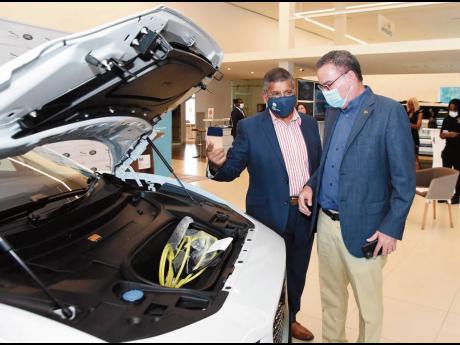 British High Commissioner to Jamaica, Asif Ahmad CMG shows Energy Minister Daryl Vaz that there’s no engine under the bonnet of the all-electric 2021 Jaguar I-Pace at its official launch on Thursday, April 8 at Stewart’s Automotive Jaguar Land Rover sh