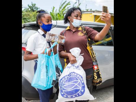 A mother and her daughter show off what they received in their care package on a video call to other family members. The care packages were delivered by New Fortress Energy Foundation and Food for the Poor to parents with students on the PATH programme in 