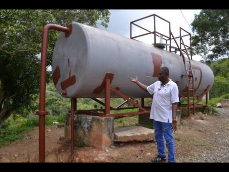 Devon Wilks, president of the Ginger Ridge Community Development Committee (CDC) in Browns Hall, St Catherine, points to the water tank that was acquired through the effort of that organisation. 