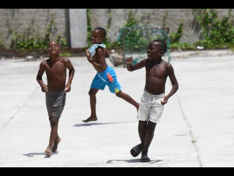 Youngsters playing on concrete in a yard in Grants Pen, St Thomas, on Saturday. There is no playing field in the community.