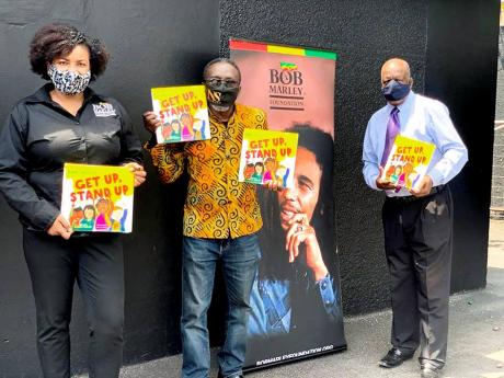 From left: Manager of the Bob Marley Foundation, Alicia Williams; Owen ‘Blakka’ Ellis, president of the Optimist Club of Trench Town; and Dr Henley Morgan, founder and chairman of Agency for Inner-City Renewal show off some of the books to be used to t
