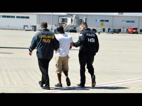 American law-enforcement officials escorting lotto scammer 28-year-old Davion Barrett of Norwood, St James, out of Jamaica in 2015. Barrett was the first Jamaican to be extradited to the US to answer charges related to the lottery scam. 