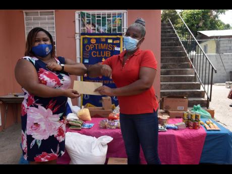 Isha A. McLeary, president of the Optimist Club of St. Matthew’s, Kingston (left), donates food items to Annette Wynter-Hill, principal of Kings and Queen Nursery and Pre-School, 35 James Street, Kingston, on Friday.  