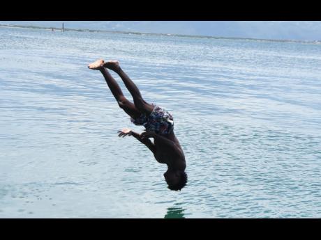 Prince Bryan, 18, leaps off the Port Royal Pier. Bryan, one of several teenagers who are members of JAPROS swimming club, edits videos of their exploits and posts them to a YouTube channel that is generating a buzz.