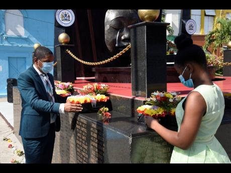 Delroy Williams, mayor of Kingston, and Reajean Bennett, acting youth mayor, pay respect by laying wreaths on the Secret Gardens Monument, in memory of children who have died tragically, at the intersection of Tower and Church streets in the capital on Sun