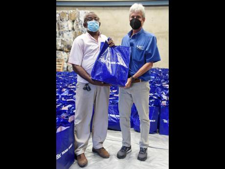 Bruce Bicknell (right), managing director of Tank-Weld Metals Ltd, hands over care packages to Carlton Byfield for distribution to needy persons in the inner city.