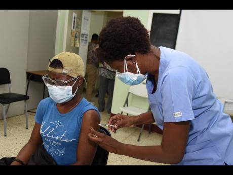 Jamaican female rugby player Dae-Marie Whyte is vaccinated by Dr Kayon Donaldson Davis at the Mona Ageing and Wellness Centre on Wednesday. She is among a group of 80 athletes scheduled to receive their first dose of the Oxford-AstraZeneca vaccine for elig
