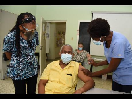 Professor Howard Spencer is vaccinated with his second dose of the Oxford-AstraZeneca vaccine by Dr Kayon Donaldson Davis at the Mona Ageing and Wellness Centre on Wednesday while his wife, Beverley Spencer, looks on. He was among the first set of persons 