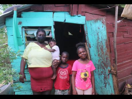 Topal Williams and three of her children stand outside their home in Schoolfield, St Elizabeth.