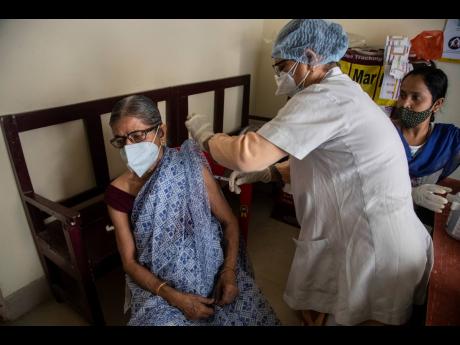 An elderly woman receives the AstraZeneca vaccine for COVID-19 at a government run clinic in Guwahati, India.