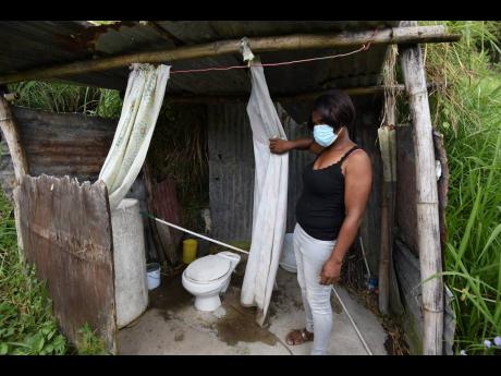Janet McKenzie shows the makeshift bathroom near the ramshackle place she calls home in Green Peas, Content Gap. 