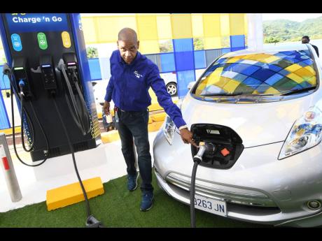 Richard Gordon, manager, Business Development, Jamaica Public Service Company charging an electric vehicle during the comissioning of the first Public Electric Vehicle Charging Station at Boots Service Station, Drax Hall, St. Ann on Friday, 