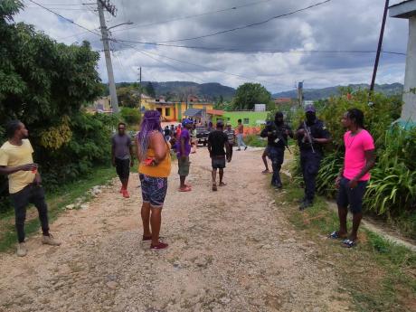 Police officers keep a close watch as residents of All-Side in Trelawny vent their anger over the alleged circumstances under which Kimorlay Forbes was killed.