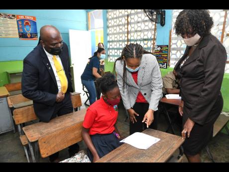 School administrators and education ministry officials assess the readiness of young Kianna Hall, student of Louise Bennett-Coverley All Age on the first day of the resumption of face-to-face classes on Monday. From left are: acting principal of Mona Heigh