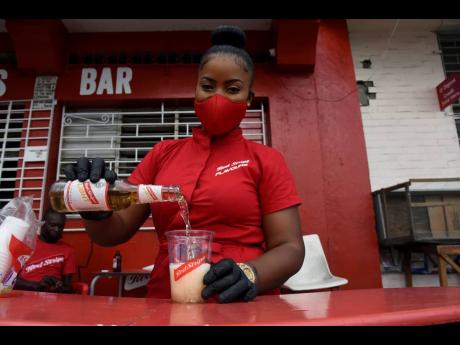 Red Stripe Brand Ambassador Sashanna Maxwell pours a cold cup of beer for customers to sip and enjoy.