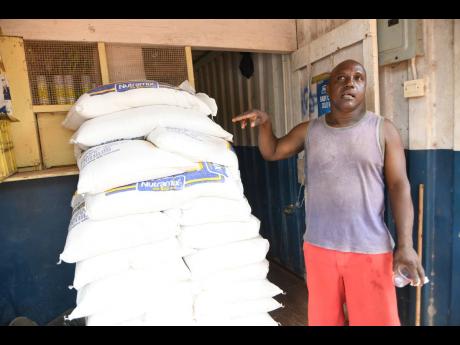 Ramunn Hanson explains some of the challenges facing him as a businessman. Here he is seen pointing to Nutramix feeds he sells from a container in Kitson Town. 