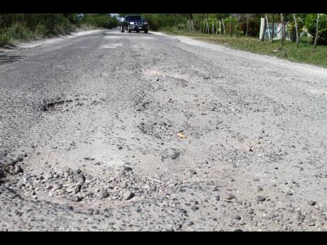 A vehicles tries to negotiate potholes on a roadway in south-west Clarendon.