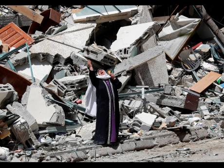 A woman reacts while standing on Sunday near the rubble of a building that housed The Associated Press, broadcaster Al-Jazeera, and other media outlets in Gaza City. The building was destroyed by an Israeli airstrike a day earlier. 