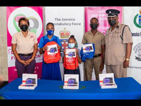 Renee Rose (left), corporate programmes manager at LASCO Distributors Limited, and Assistant Commissioner of Police, Community Safety and Security Branch, Ealan Powell, share a photo with Kiara Summerbell (second left), Aniyah McKenzie (centre), and Deshau