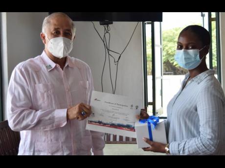 Chairman of Caribbean Cement Company Limited, Parris Lyew-Ayee (left), presents final year civil engineering student at The University of the West Indies, Mona and CEMEX Campus 2021 participant, Lesmar Murray with a certificate and token at the company’s