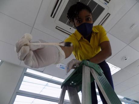 An ESL worker swabs a HVAC System to test for yeast and mould in an office building.