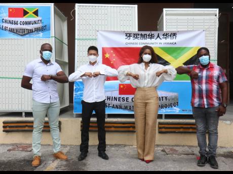 Member of Parliament for South East St Ann Lisa Hanna (second right) and Yangsen Li (second left), representative of the Jamaican Chinese community, bump elbows with Moneague resident Romaine Thomas (left) and Ricardo Riley, who is from the Claremont area 