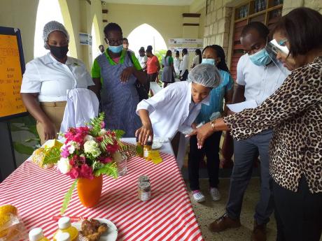 Pauleen Reid (far right), principal of Knockalva Polytechnic College, and agro-processing tutor Murphy Gooden are seen giving tips to students who were displaying their products at the institution last Friday.