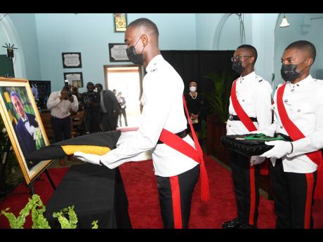 From left: Sgt Leonard Gordon, Sgt Hoshane Lennon and Tarik Pryce with the national flag and the Insignia of the Order of Jamaica, which was accorded to the late Ambassador Anthony Johnson, at his memorial service at Kingston College’s St Augustine Chape