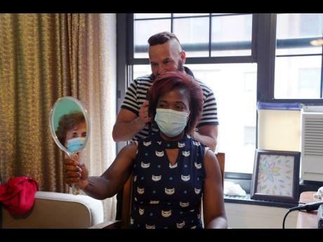 Elizabeth Deterville looks at her new hairstyle courtesy of stylist Roberto Novo in an apartment in New York. Novo started offering older clients free haircuts during the coronavirus pandemic. 