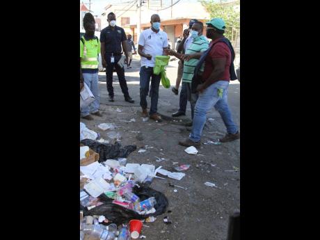Businessman Gary Douglas (second right) shows Edward Muir, regional operations manager, SPM Waste Management Ltd, an area along Stork Street, Clarendon, where persons dispose of their garbage, on Wednesday, June 2. 