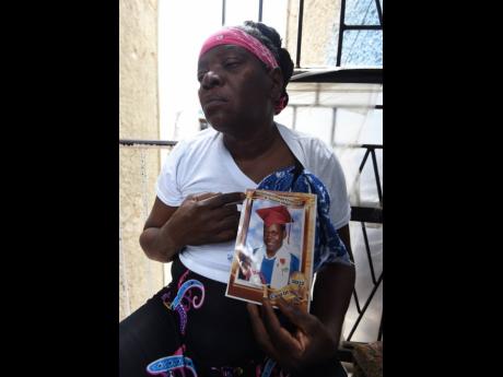 Barbara Richards mourns as she holds a picture of her son, Shedaine Richards, who was fatally shot by gunmen along Rum Lane in the Kingston Central Police Division while on his way home from work on Wednesday night.