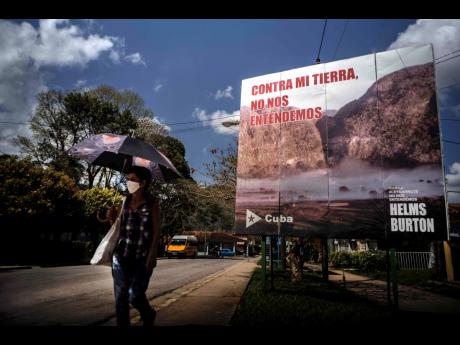 
A woman walks past an anti-embargo sign that reads in Spanish: “Against my land, we don’t understand each other”, in Viñales, Cuba, on March 1, 2021. 