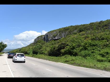 Motorists drive by a section of the limestone-rich Puerto Bueno Mountains, which have been a source of much contention over the past year.
