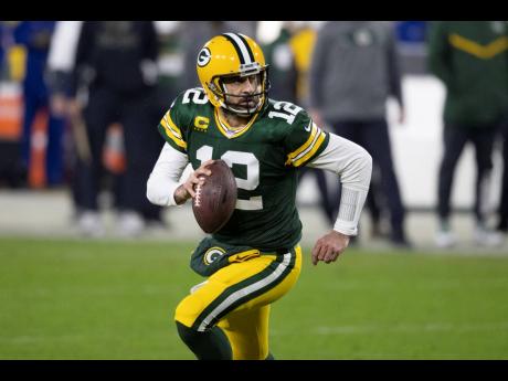 In this January 16, 2021, file photo, Green Bay Packers quarterback Aaron Rodgers runs with the ball during the team’s NFL divisional playoff football game against the Los Angeles Rams in Green Bay, Wisconsin. Rodgers’ teammates say the MVP’s uncerta