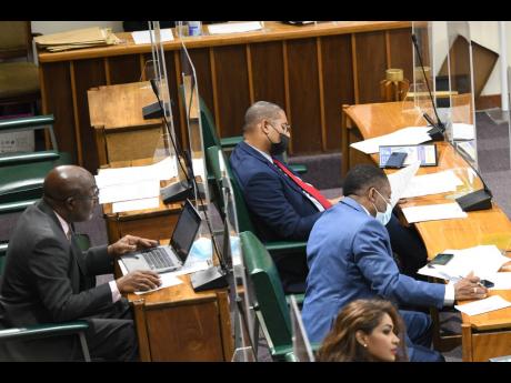Mikael Phillips (centre), opposition member of parliament for Manchester North West, participates in a sitting  of the House of Representatives on Tuesday. Under-fire Westmoreland Central MP George Wright sat to the left of Phillips briefly on Tuesday, cut