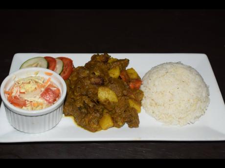 Curried goat served with the customary white rice and serving of raw vegetables.