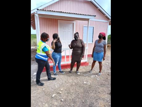 From left: Kivette Silvera, executive director, Food For The Poor; Keteisha McHugh, brand manager, BOOM Energy Drink, presenting Cislyn Williams with the keys to her home. Looking on is Cisyln’s mother, Joan Williams.