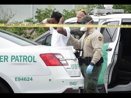 United States Border Patrol officials detain one of 14 migrants who came ashore on the intracoastal waterway in Pompano Beach, Florida, on Thursday. Several of them are believed to be Jamaicans.