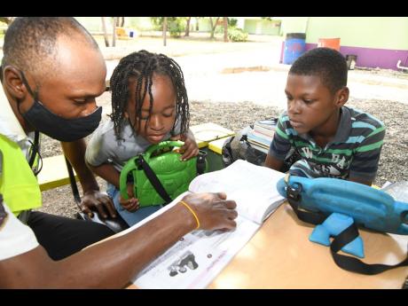 Shawn Muir (left), a security guard at Liberty Academy at Priory in St Andrew, takes his sons, six-year-old Nashawn and 10-year-old Dai-Shawn, to work with him so that he may help with their online schooling. 