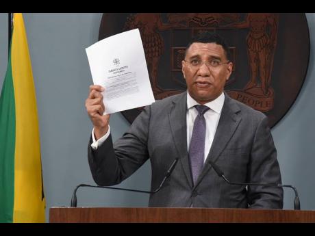 Prime Minister Andrew Holness displays the gazetted order declaring Norwood a zone of special operations on Sunday. Holness was addressing a Jamaica House press conference.