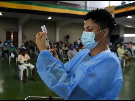 Sasha Johnson, a registered midwife, prepares to administer the Oxford-AstraZeneca COVID-19 vaccine for persons 50 and older who turned out for their second dose at the National Arena on Saturday, June 19.