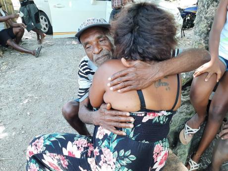 Rupert Wachope comforts one of his nieces, Keisha Silvera, on the passing of her father, Leric Silvera. 
