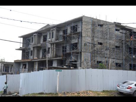A labourer is seen outside a multi-storey apartment under construction at the intersection of Charlemont Drive and Finchley Avenue in Hope Pastures, St Andrew, on Thursday.