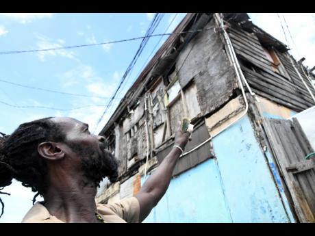 Hopeton Harris points to a two-storey board home in Denham Town, Kingston, where he lives. Harris fears the structure is at risk of tumbling. 